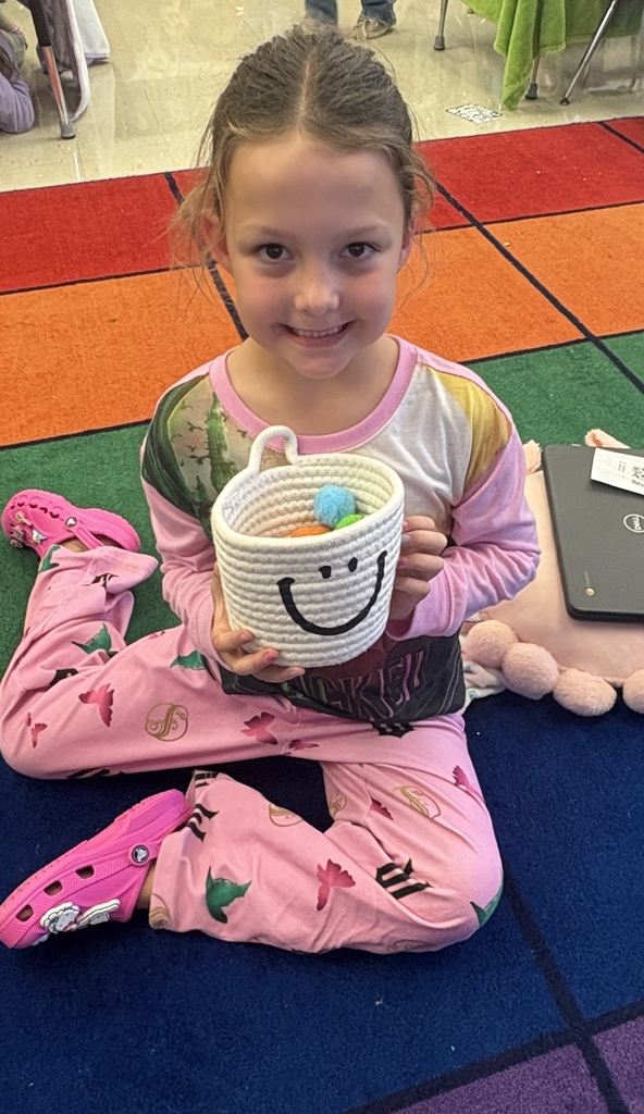 1st grade student with the puff ball bucket they filled to earn their PJ and fort day
