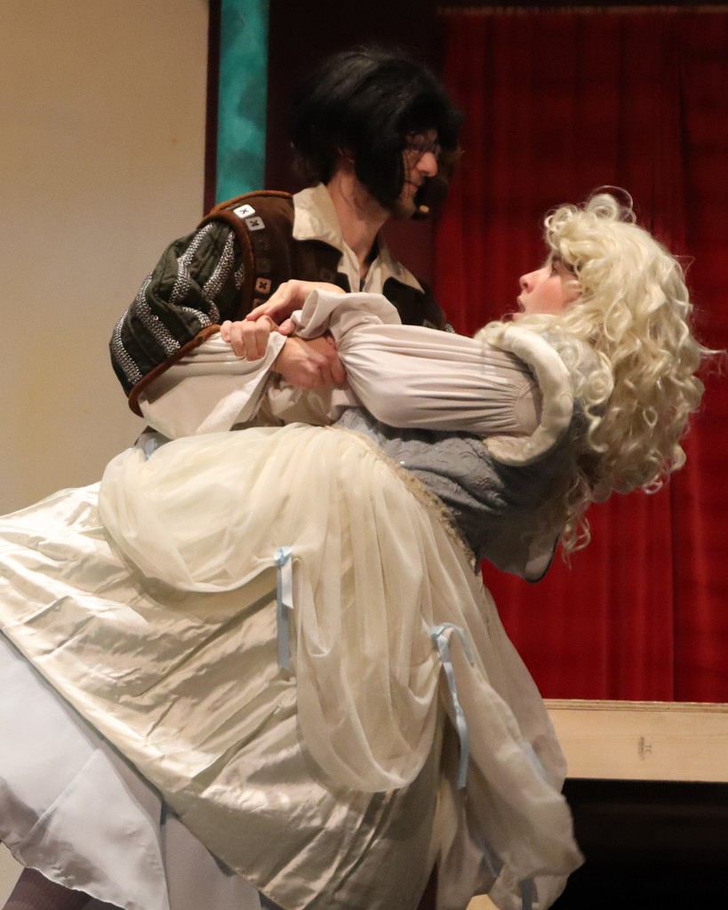 In full Shakespearean costume, one actor dips another