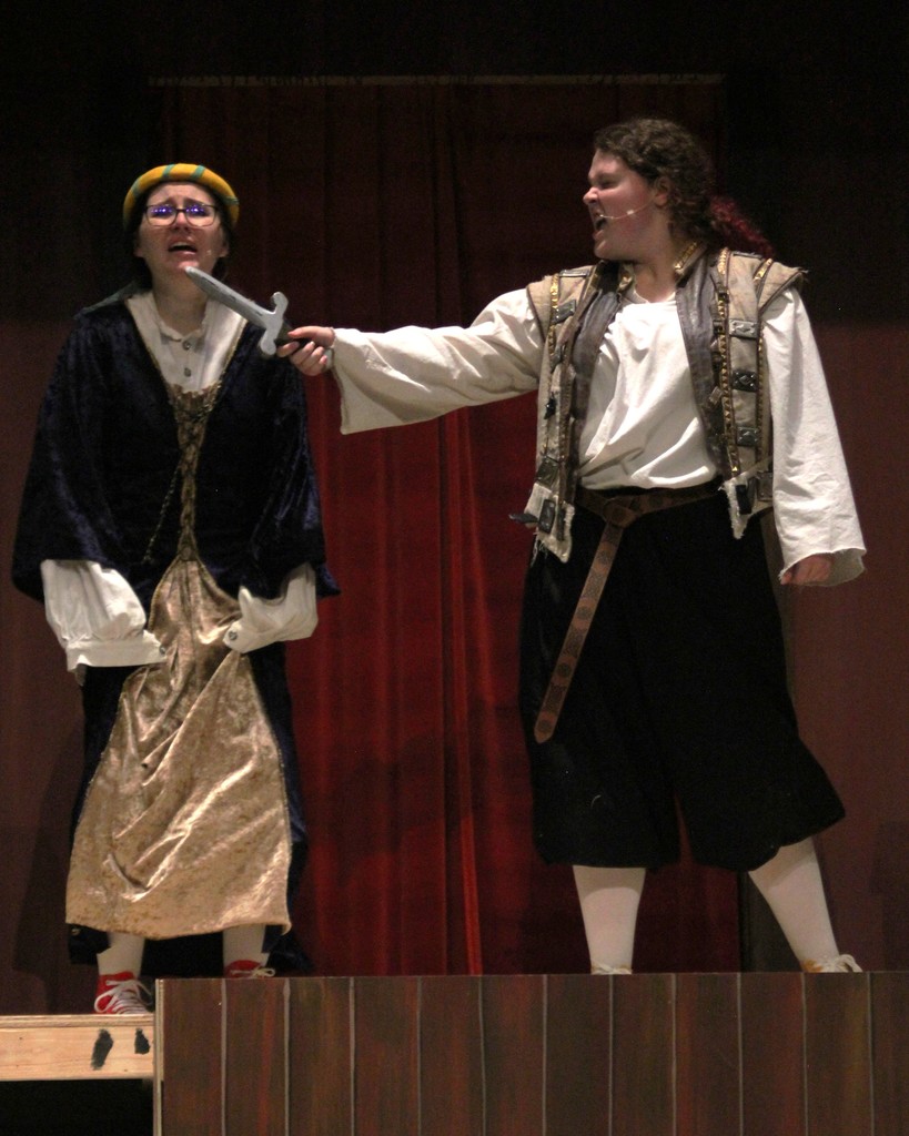 Student actors on stage portray an argument