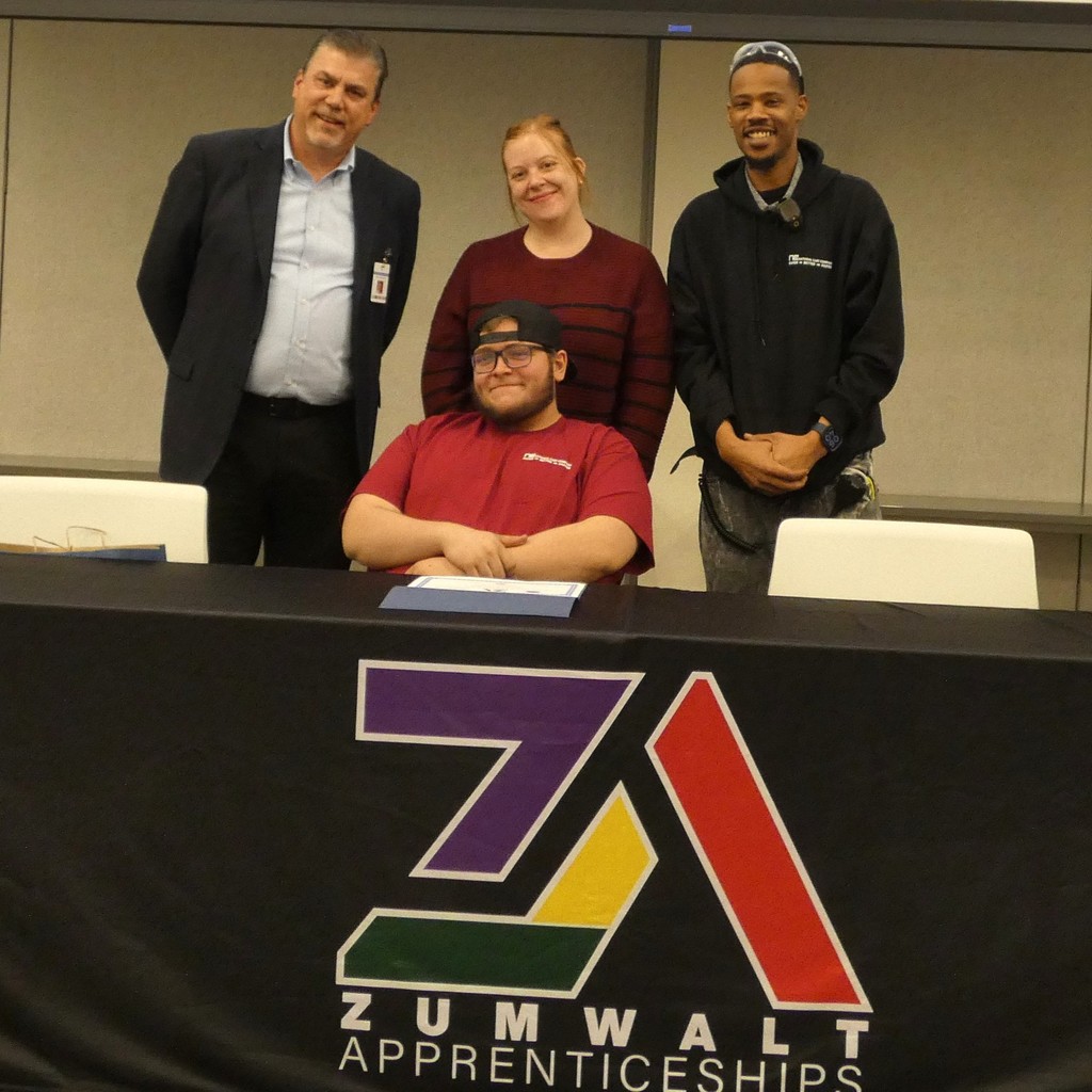 Certified apprentice receives his certificate at signing table with employers