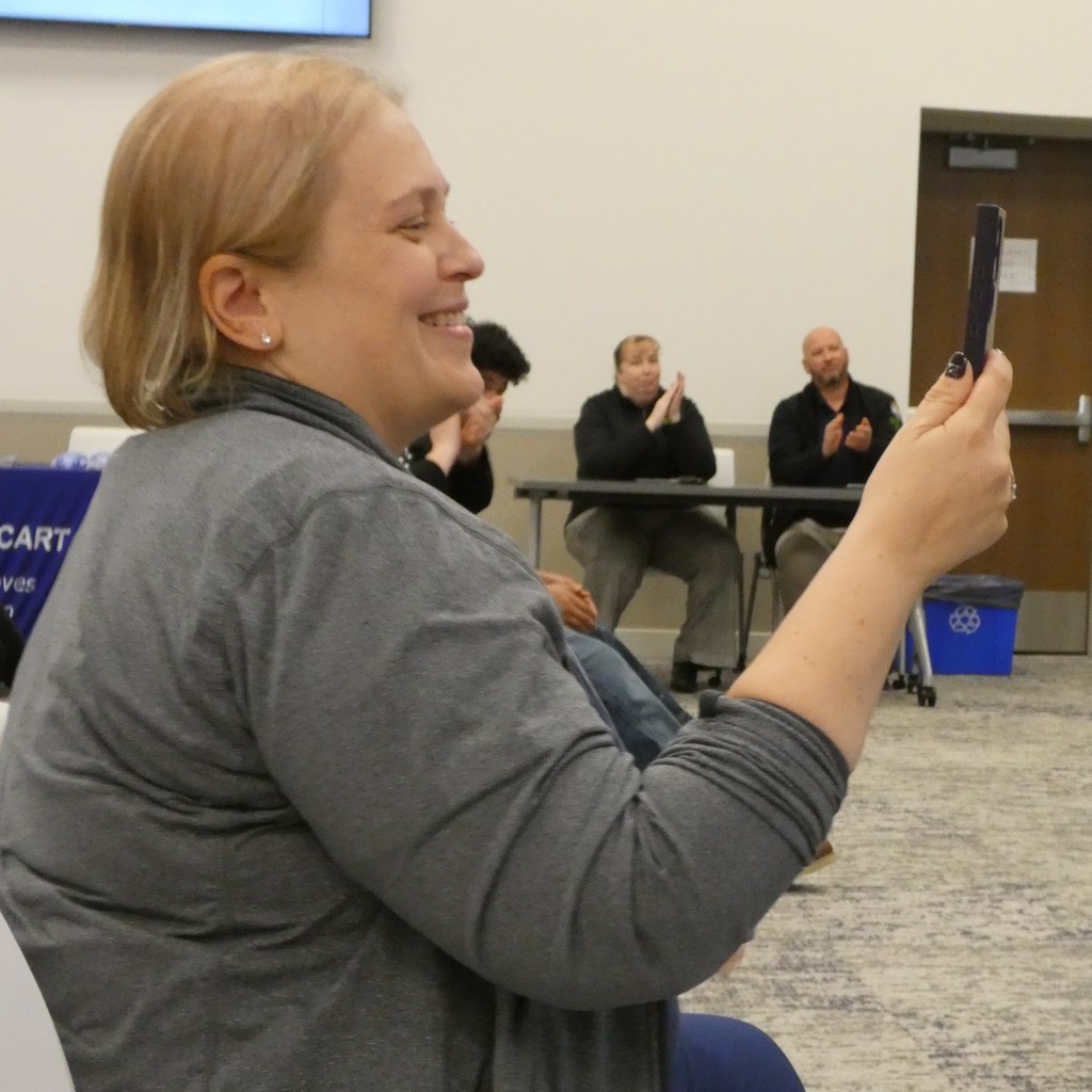 proud family member uses phone to video remarks from employer about newly certified apprentice