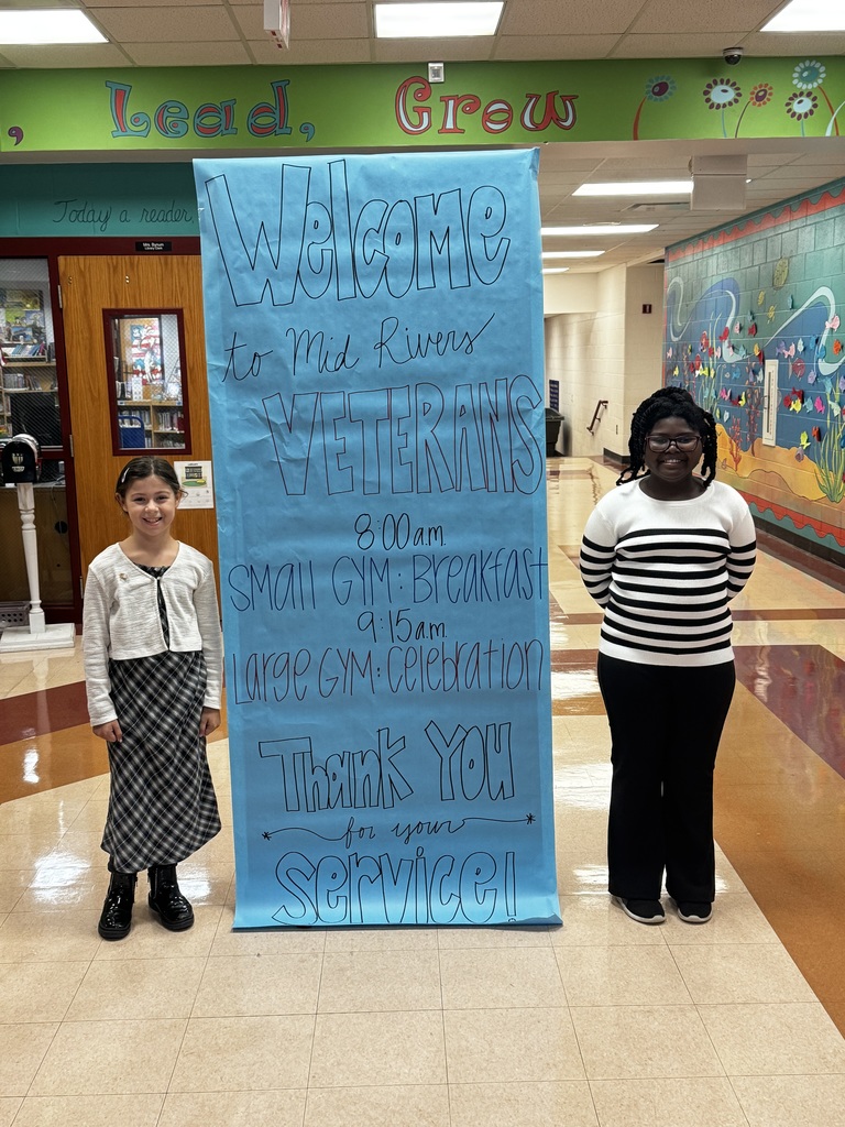 Student greeters welcoming veterans at the front doors. The sign read: Welcome to Mid Rivers Veterans 8:00am- Breakfast 9:15am- Assembly Thank you for your service.