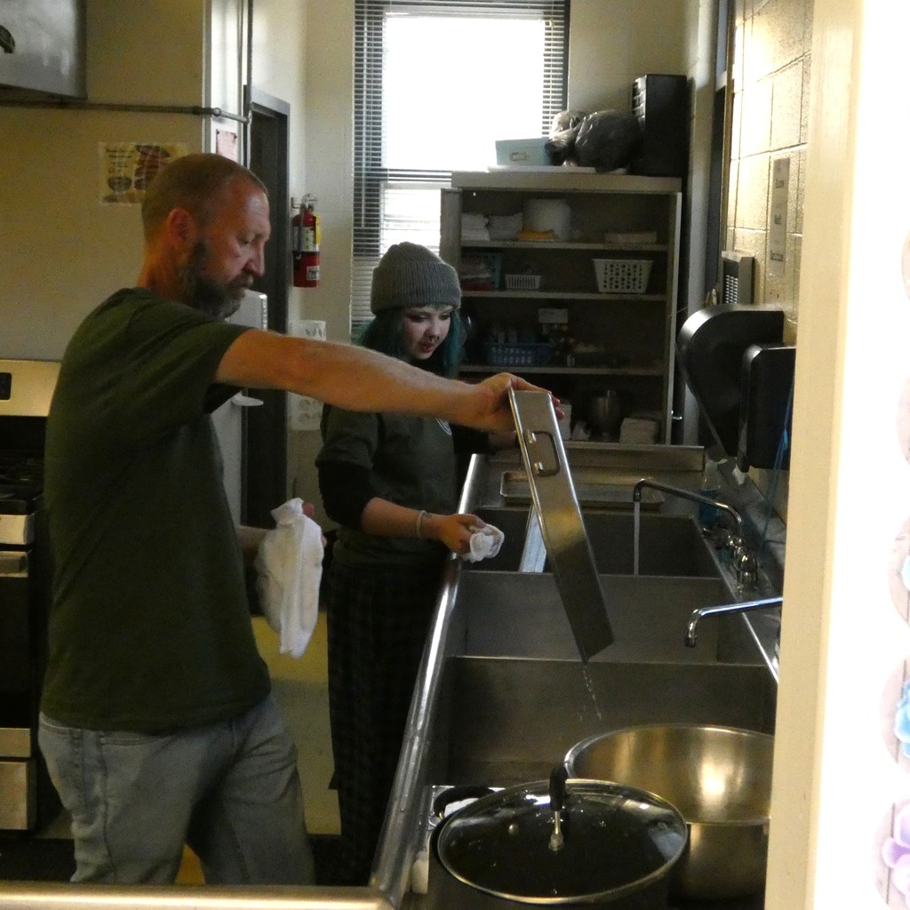 Staff member and student work the dishline together.