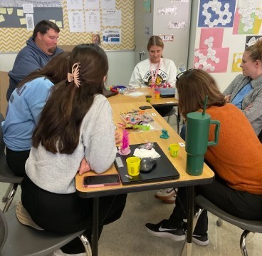 English teachers sitting at desks learning a new engagement activity for students using playdough.