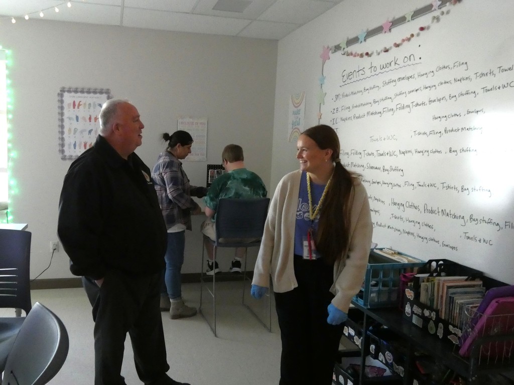 Legislator and teacher share a smile as she explains assignments on the board