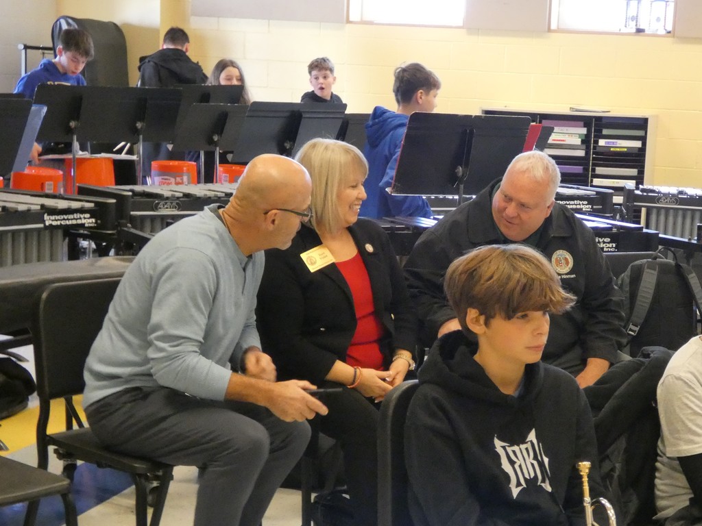 Reps sit between the percussion and brass sections visiting with staff