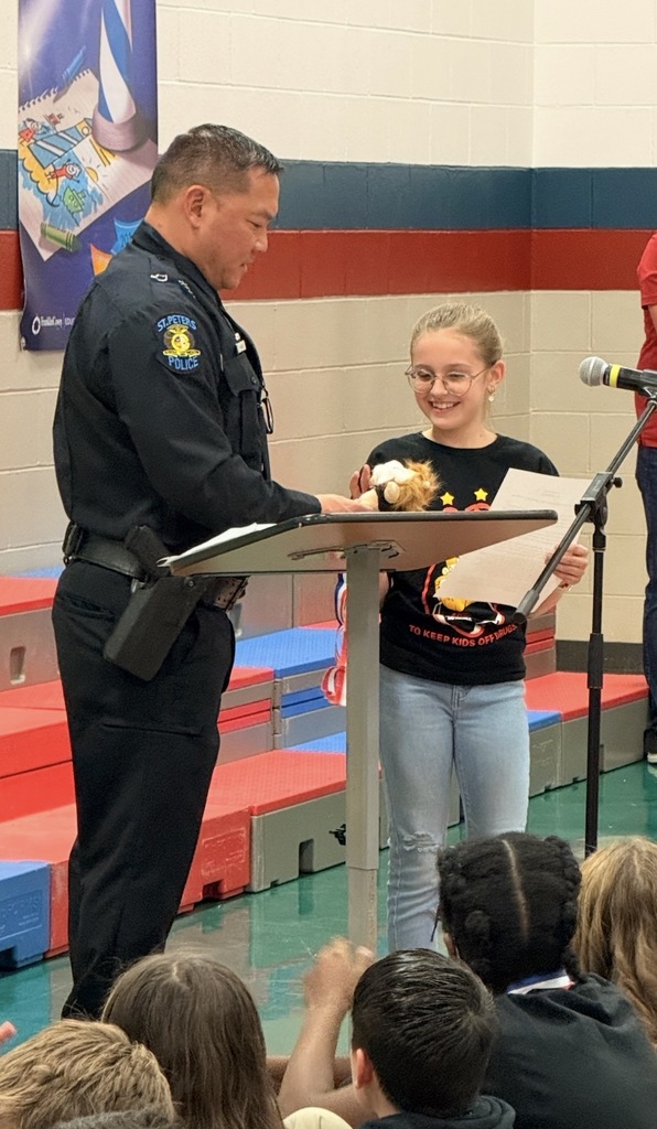 Officer Luu standing with a fifth grade student as she read her DARE essay.