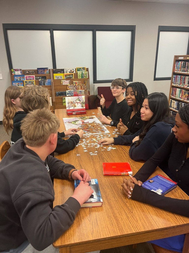 Mr. Van Liere's 8th Grade ELA working on a puzzle in the Library. 