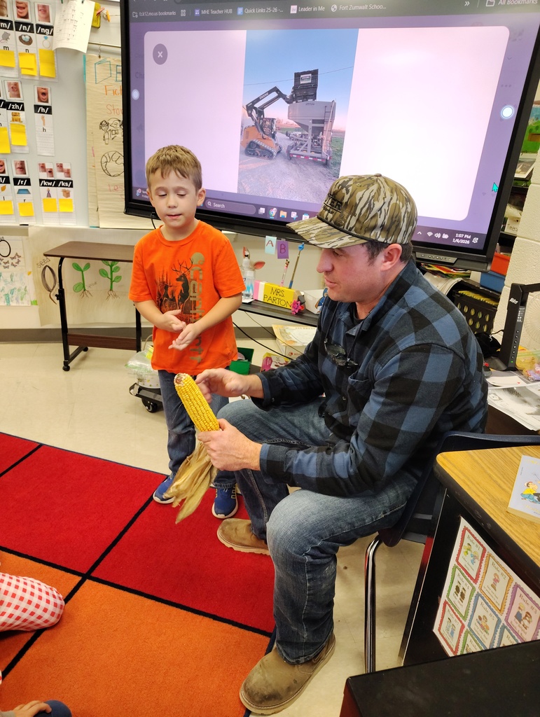 Farmer Dyer shows the type of crop he grows (an ear of corn) to the class