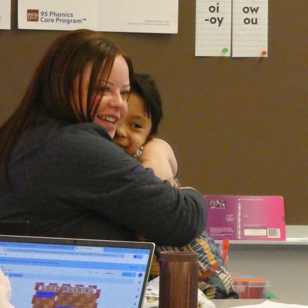 Student and teacher smile broadly as they hug when greeting each other back to class after snow storm