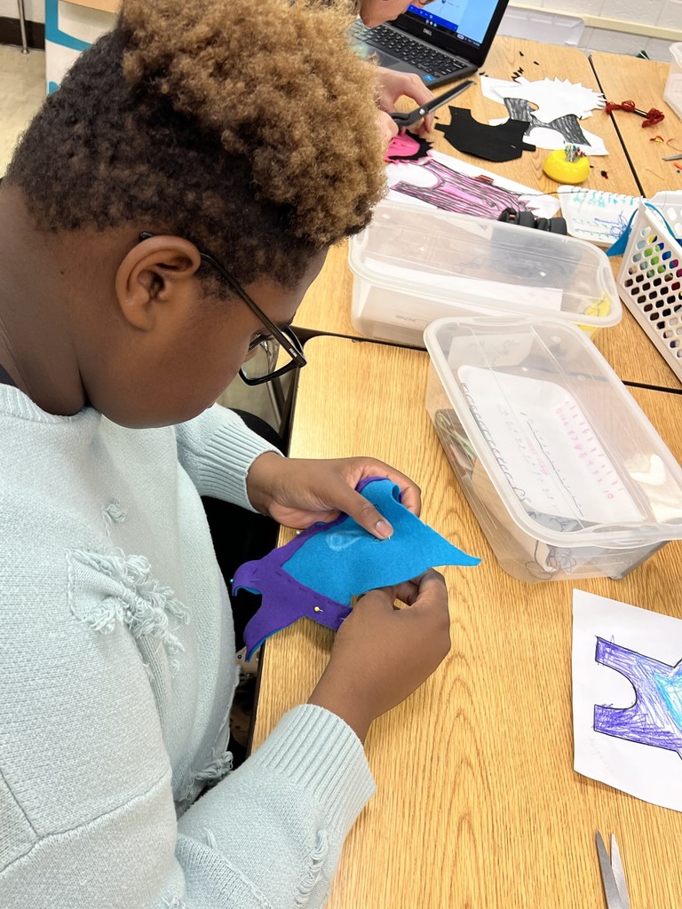 In class at South Middle a student carefully crafts a felt monster from a Kindergartener's drawing