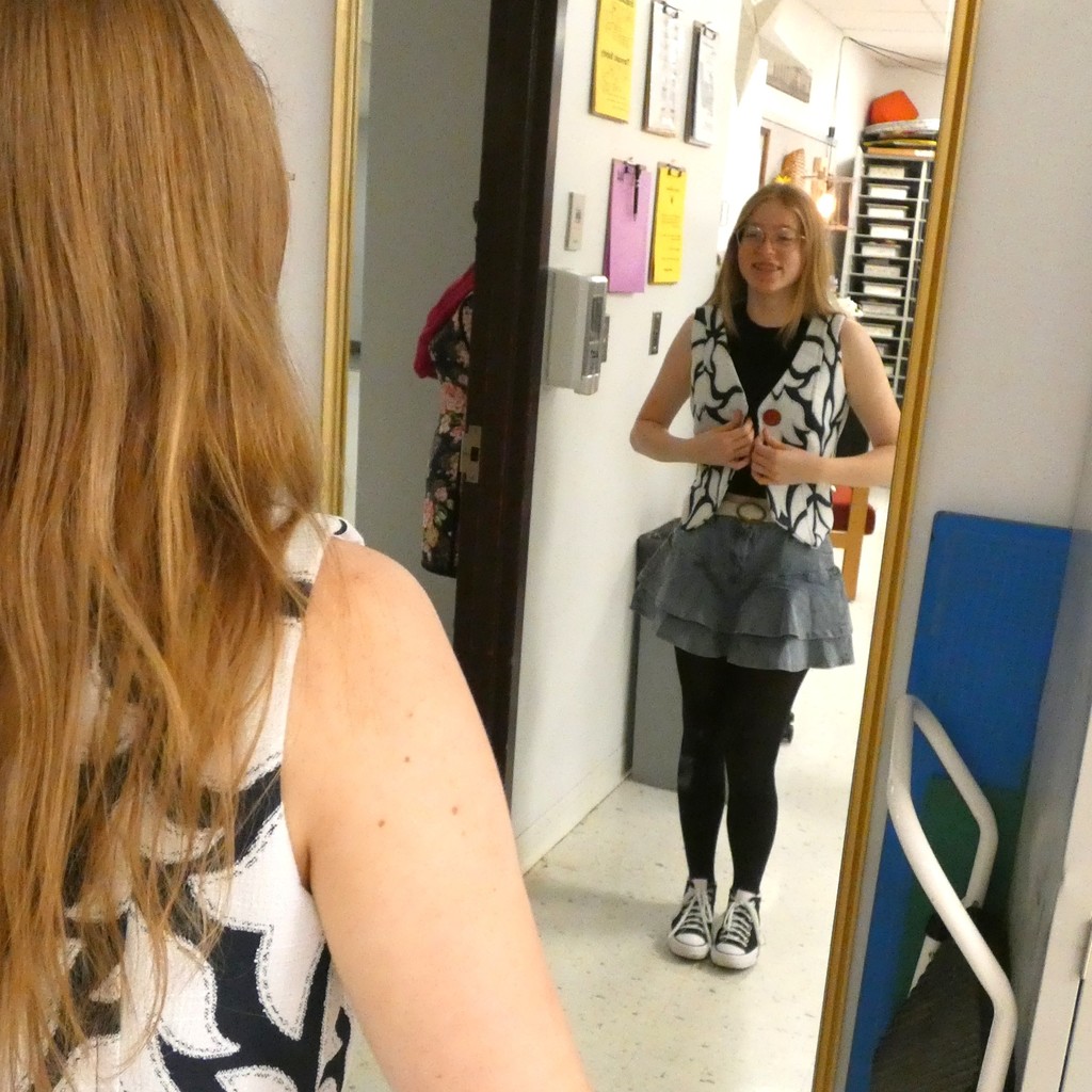 Student trying on vest smiles at reflection in mirror  