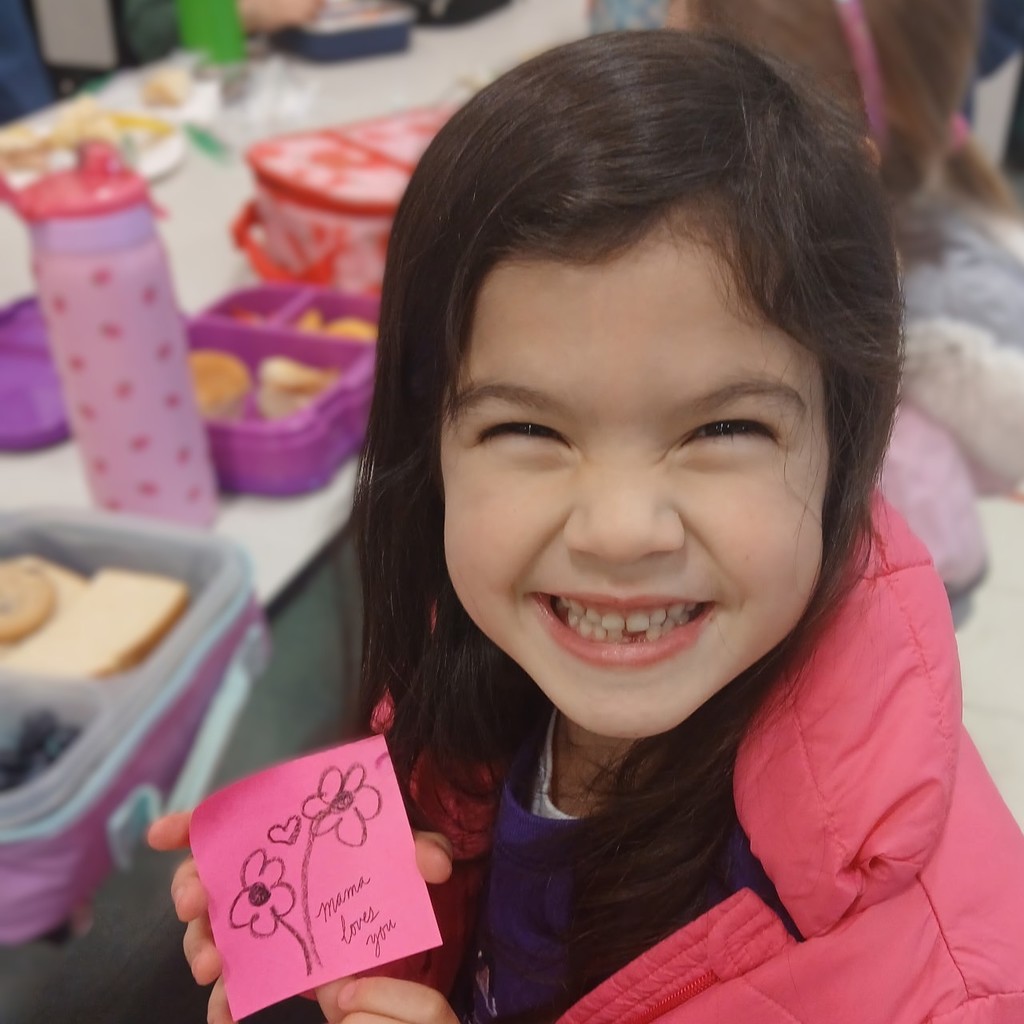 Student holds flower doodle on a post-it that syas Mama Loves You