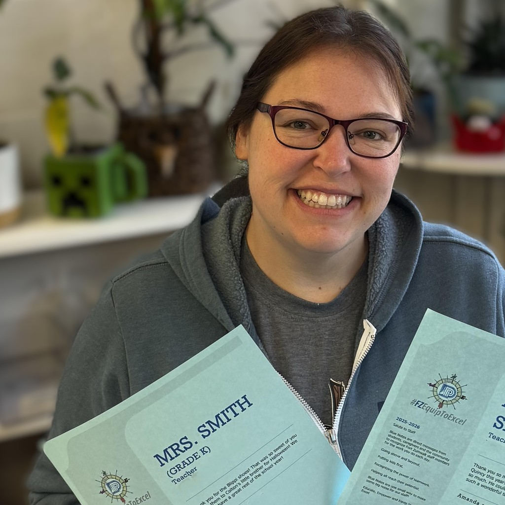 A teacher smiles holding up Blue Notes