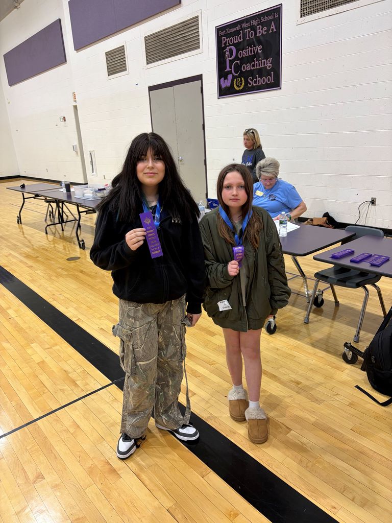 Two girls holding gold medals!  They won the STEAM Challenge! 