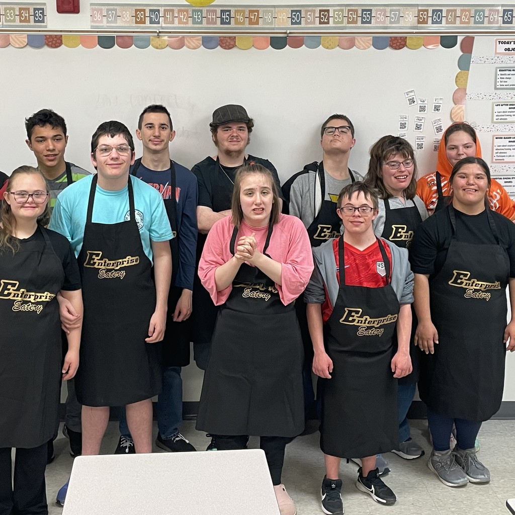 Students in black and gold aprons take a break for a group picture