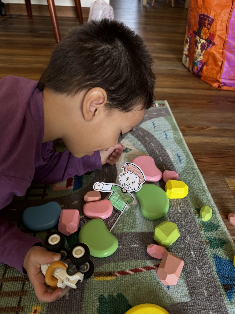 Preschooler plays with blocks, truck and Flat Stanley on the floor