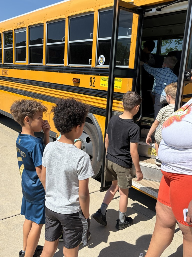 A bus driver helps students practice bus safety.
