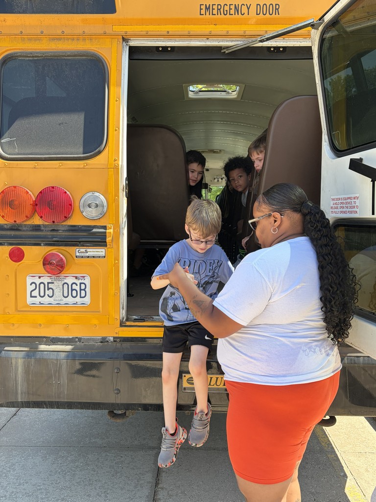 A bus driver helps students practice bus safety.