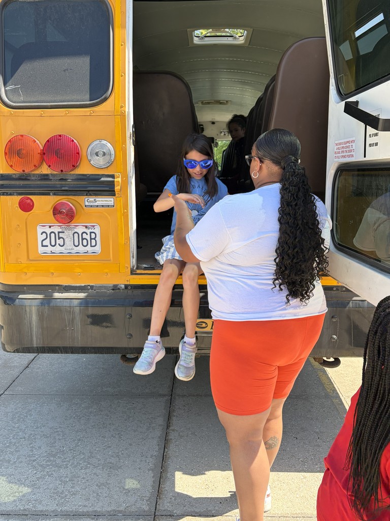 A bus driver helps students practice bus safety.
