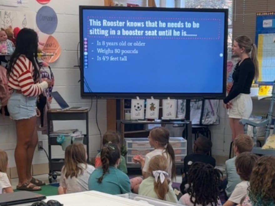 High school students present on the big screen to K-2 students