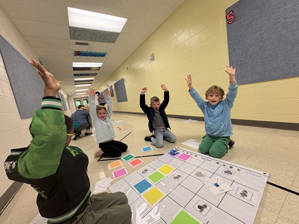 A group 1st-grade students celebrating their robot making it to their goal 