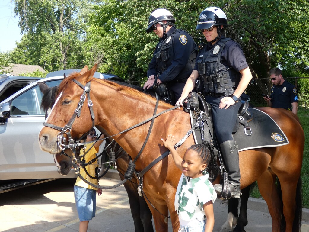 students pet horse while mounted patrol officers look on
