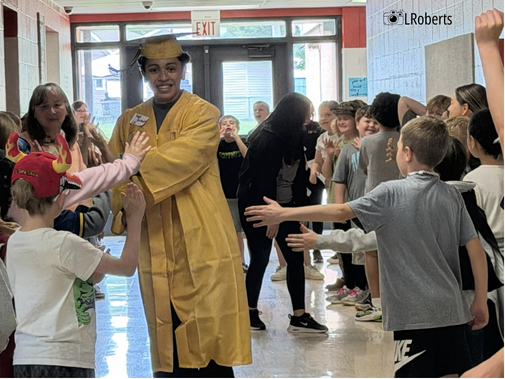 grad in cap and gown high fives elementary students