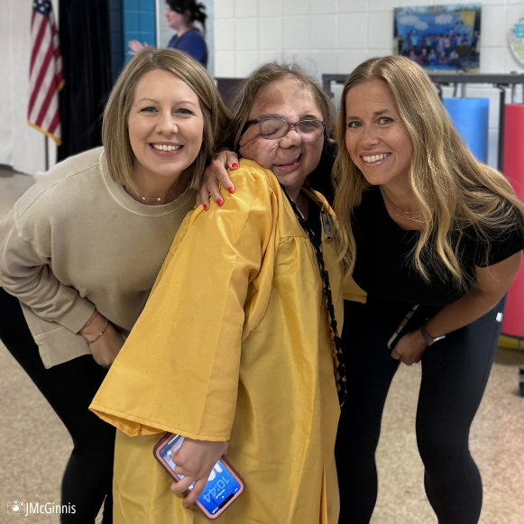 teachers pose with student in cap and gown