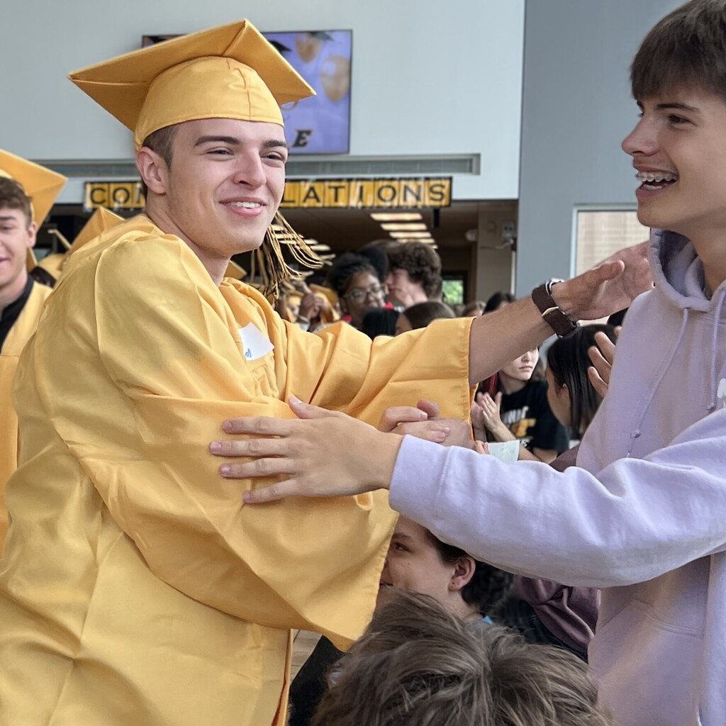 middle school student congratulates grad in cap and gown