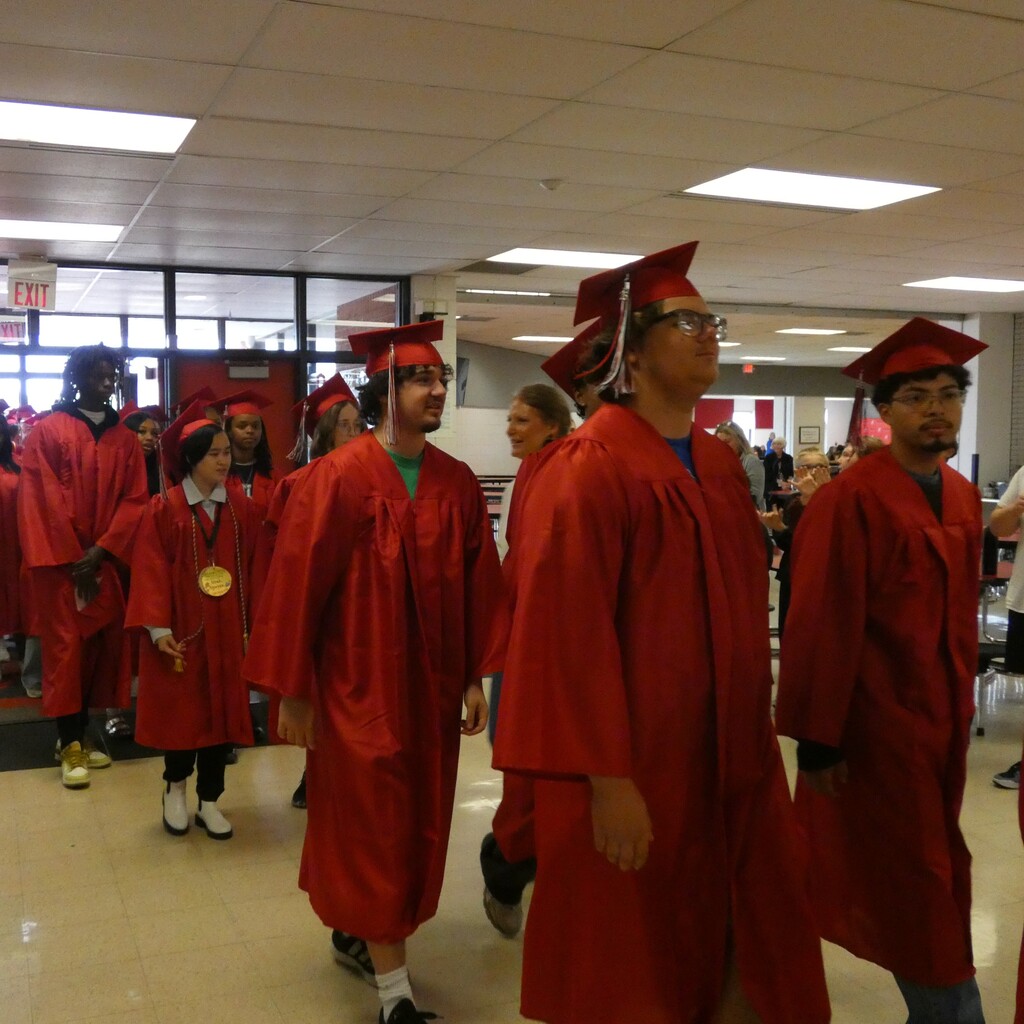 grads in caps and gowns file through middle school
