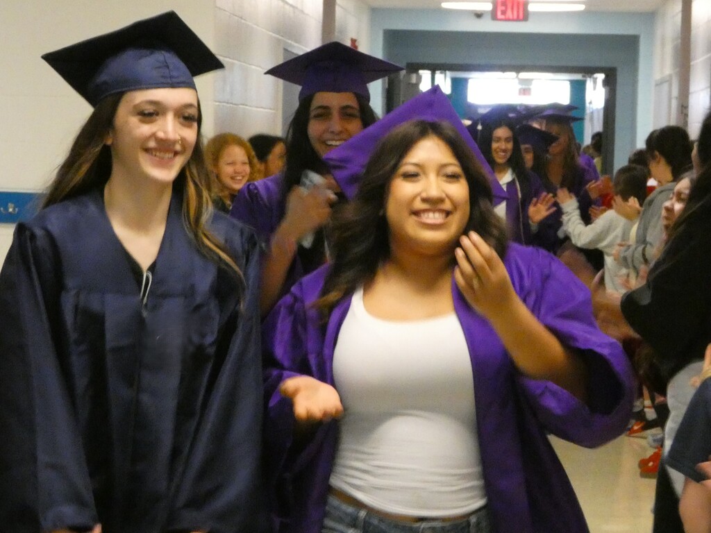 grads smile as elementary students applaud