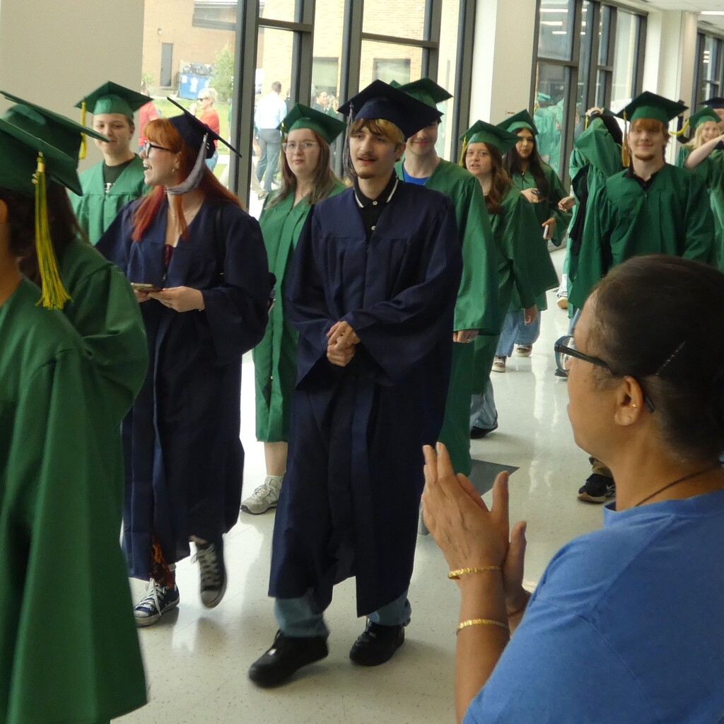 teacher applauds grads as they walk hall