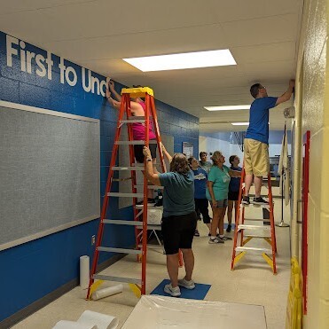 volunteers apply vinyl letters to school hallway