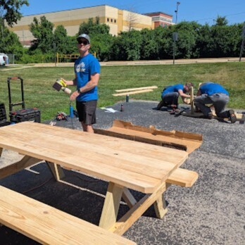 volunteers sand and assemble picnic tables