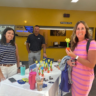 Teacher smiles picking up plastic yellow flower
