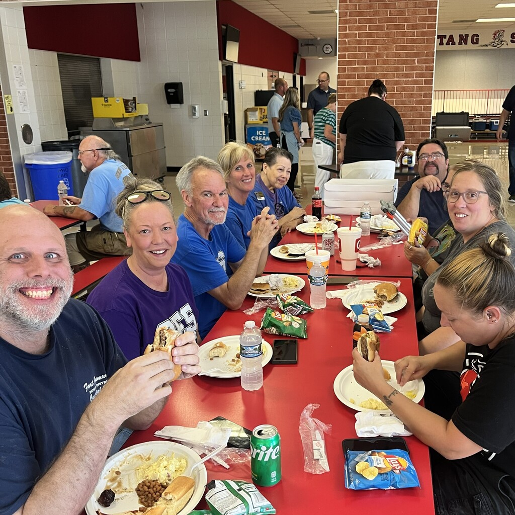 Table full of custodians break from burgers to smile for the camera