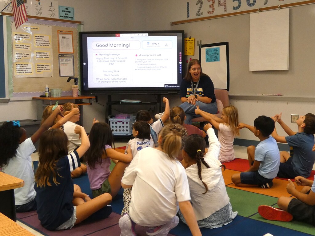 teacher shares surprise with students on carpet
