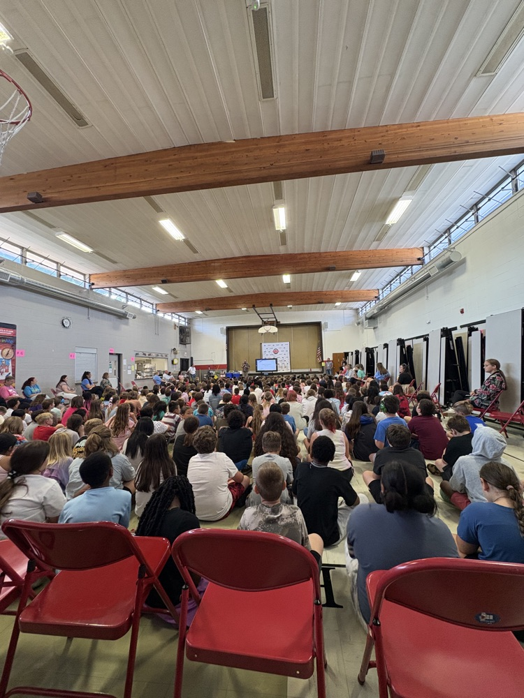 the LCE student body seated on a gym floor