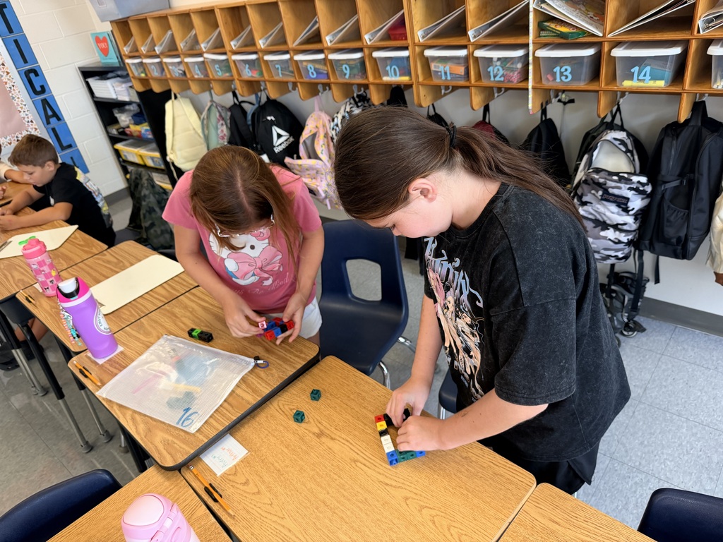 Two students are working in math groups at their desks.