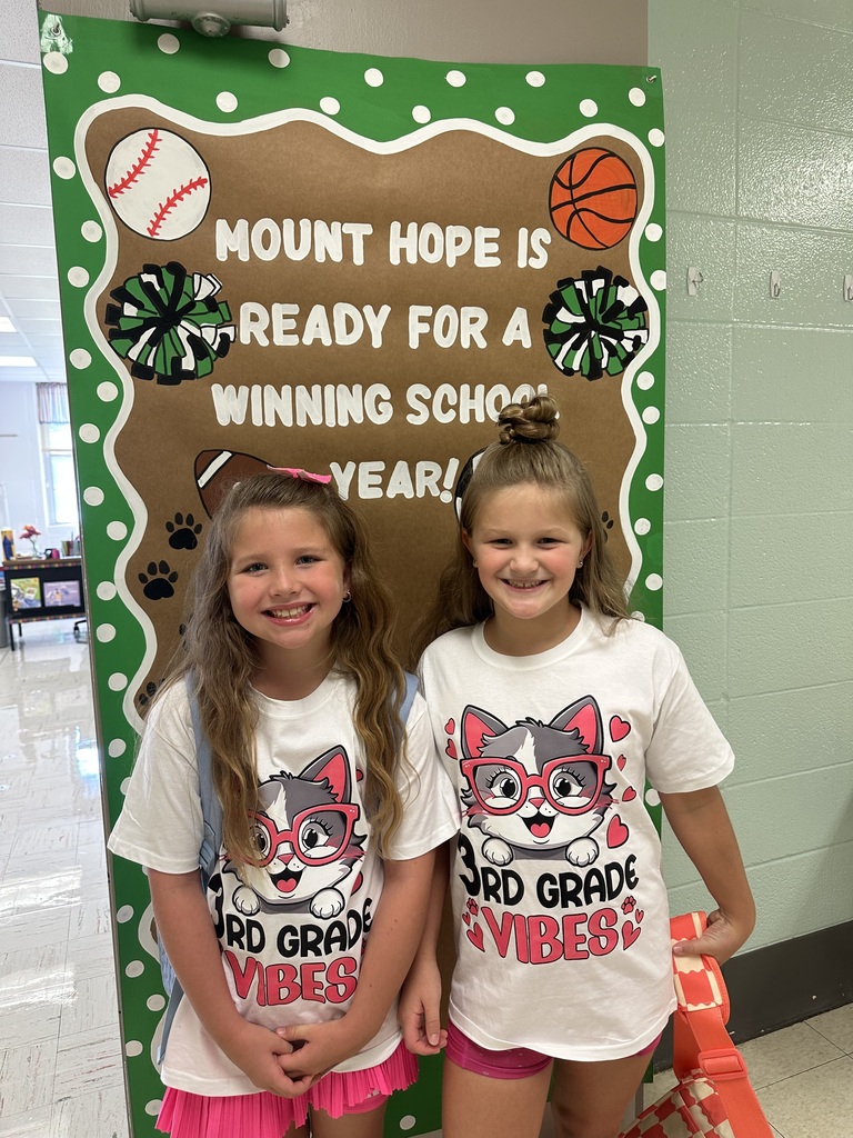 Two students wearing shirts that say 3rd Grade Vibes in front of a door that says Mount Hope is Ready for a Winning School Year!