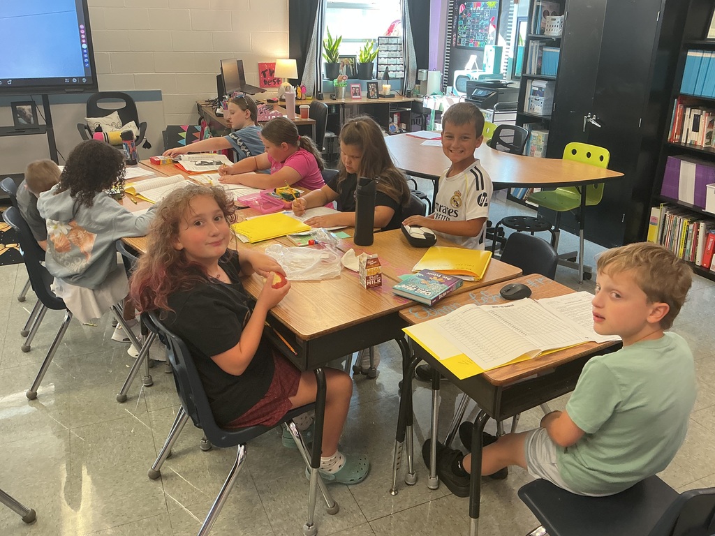 Students working at a table together on morning worksheets.