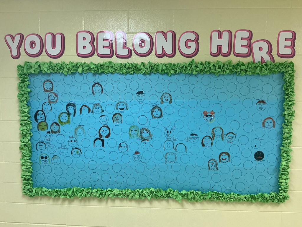 A bulletin board that says you belong here with student faces on it.