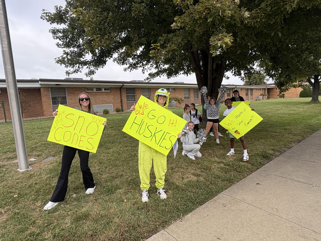 Teachers and students holding signs in support of a school fundraiser.