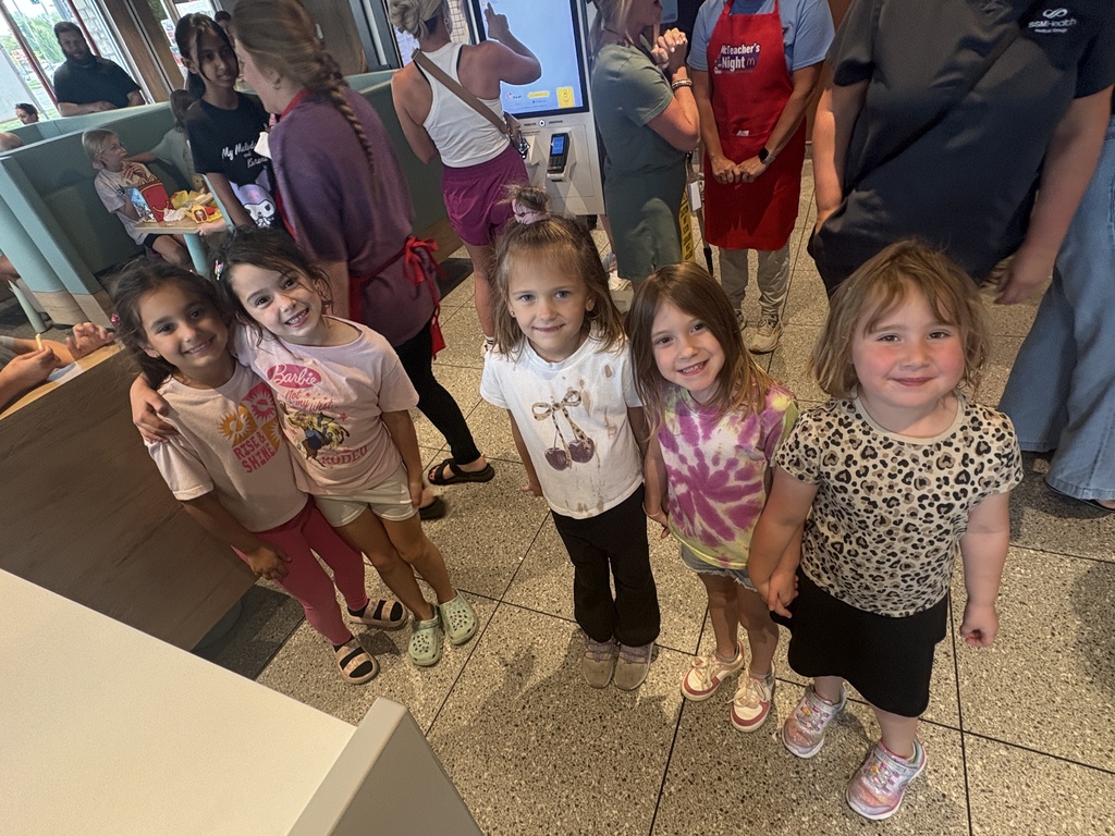 Five girls waiting in line for food at a restaurant.
