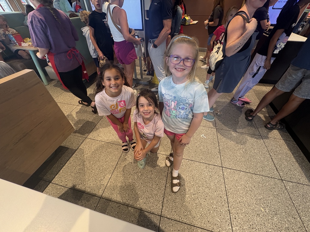 Three girls waiting in line for food at a restaurant.