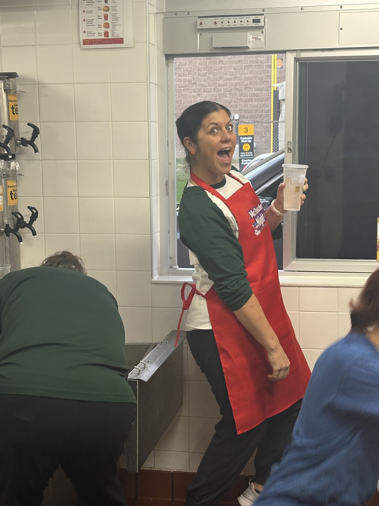 A teacher serving a customer at a drive-thru window at a restaurant.