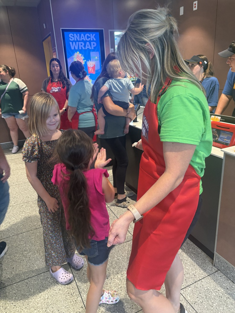 A teacher greeting two students at a restaurant.