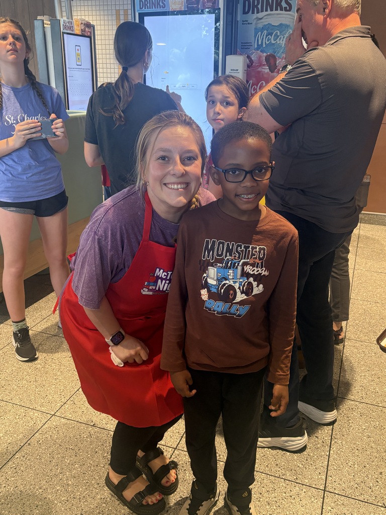 A teacher standing next to a student. Both are smiling.