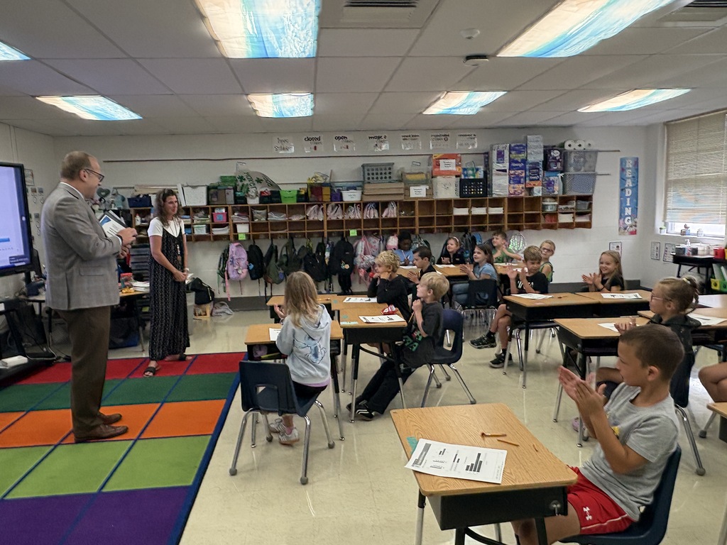 A man speaking to a classroom full of students.